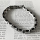 Pulsera de hilo grueso negro con huesos de acero